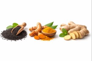 Black cumin seeds, turmeric root, and ginger root placed side by side on a neutral surface.